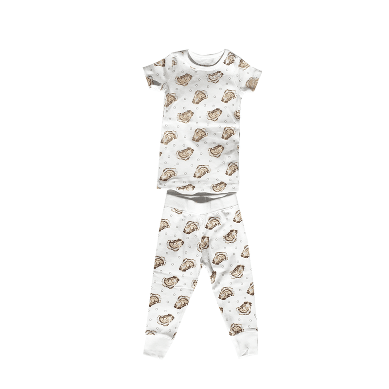 Toddler wearing "Aw Shucks" oyster-themed pajamas, smiling and holding a toy oyster, on a white background.