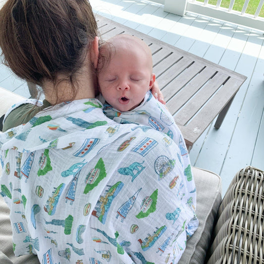 Chicago-themed baby gift set with muslin swaddle blanket and burp cloth/bib combo, featuring city landmarks.