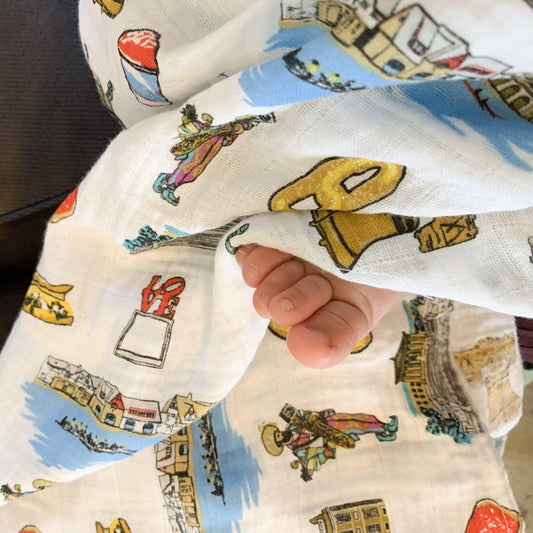 Philadelphia-themed baby gift set with muslin swaddle blanket and burp cloth, featuring iconic city landmarks.