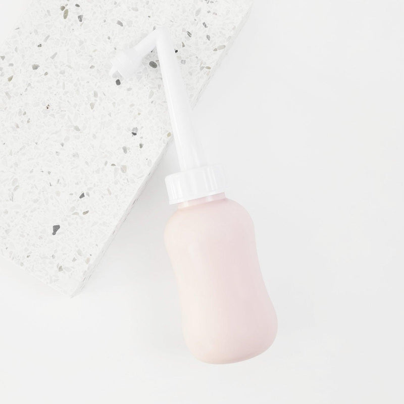 peri bottle for postpartum recovery laying on a terrazzo tile