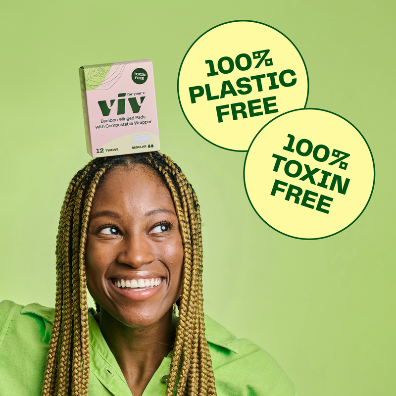 A smiling woman is balancing a box of earth-friendly pads on her head. The pads are plastic free and toxin free.