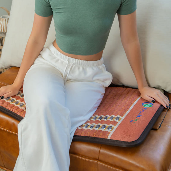 A woman lying on a TAO Series PEMF Infrared Heating Mat for pain relief and relaxation