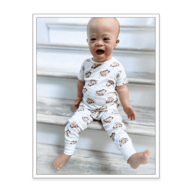 Woman in oyster-patterned pajamas, smiling and holding a mug, standing in a cozy, well-lit kitchen.