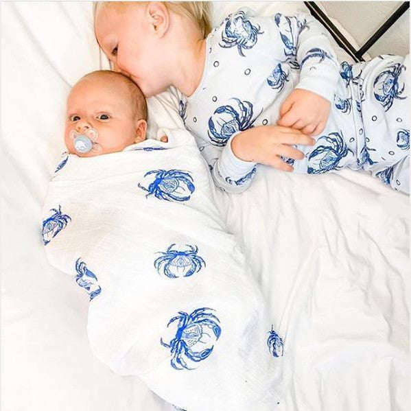 Blue crab-themed baby muslin swaddle blanket and burp cloth set, featuring playful crab illustrations on white fabric.