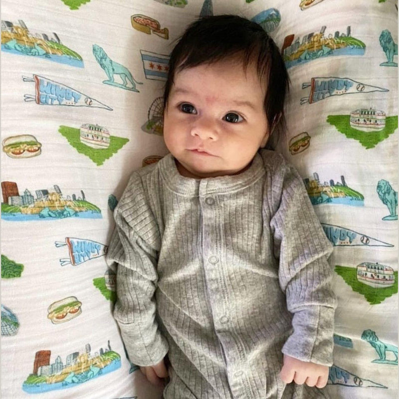 Chicago-themed baby gift set with muslin swaddle blanket, burp cloth, and bib featuring iconic city landmarks.