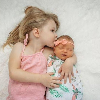 Floral-themed baby muslin swaddle blanket and burp cloth set, featuring vibrant pink and green flowers.