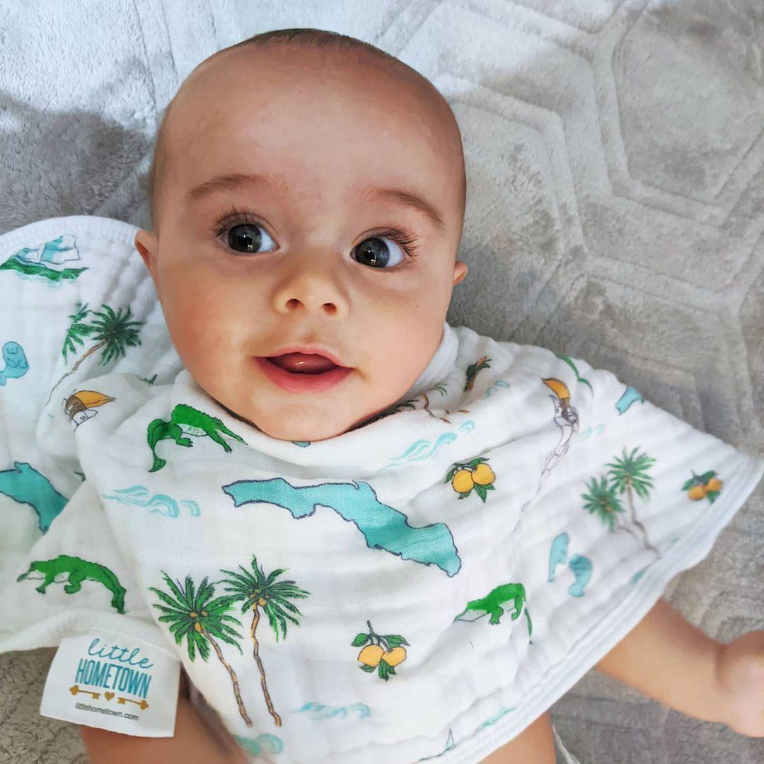 Florida-themed baby gift set with a muslin swaddle blanket and burp cloth, featuring oranges and palm trees.
