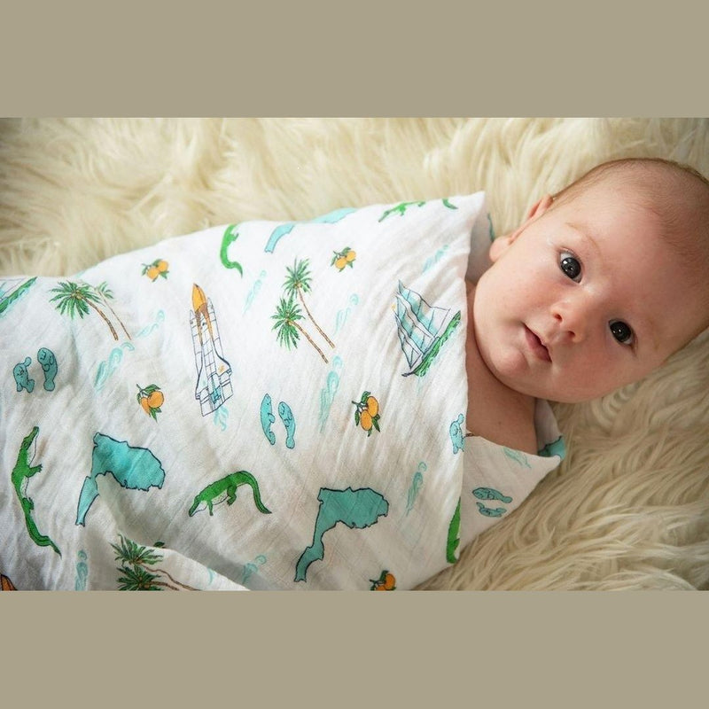 Florida-themed baby gift set with muslin swaddle blanket and burp cloth, featuring orange and green citrus prints.