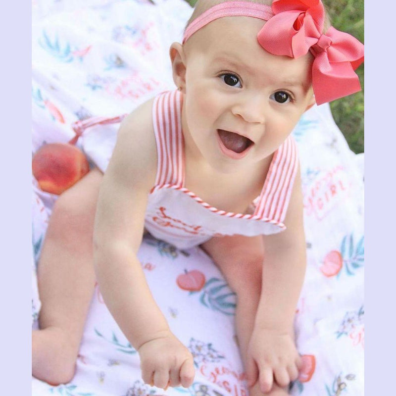 Gift set with a Georgia Girl muslin swaddle blanket and burp cloth/bib combo, featuring peach and floral designs.