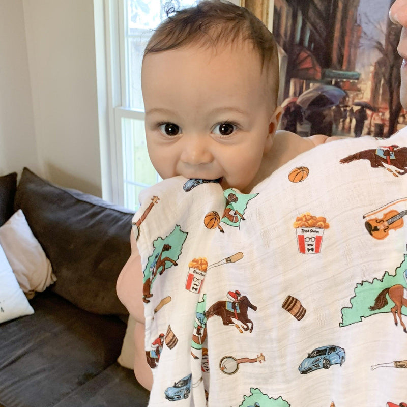Kentucky-themed baby gift set with muslin swaddle blanket and burp cloth, featuring state icons and landmarks.